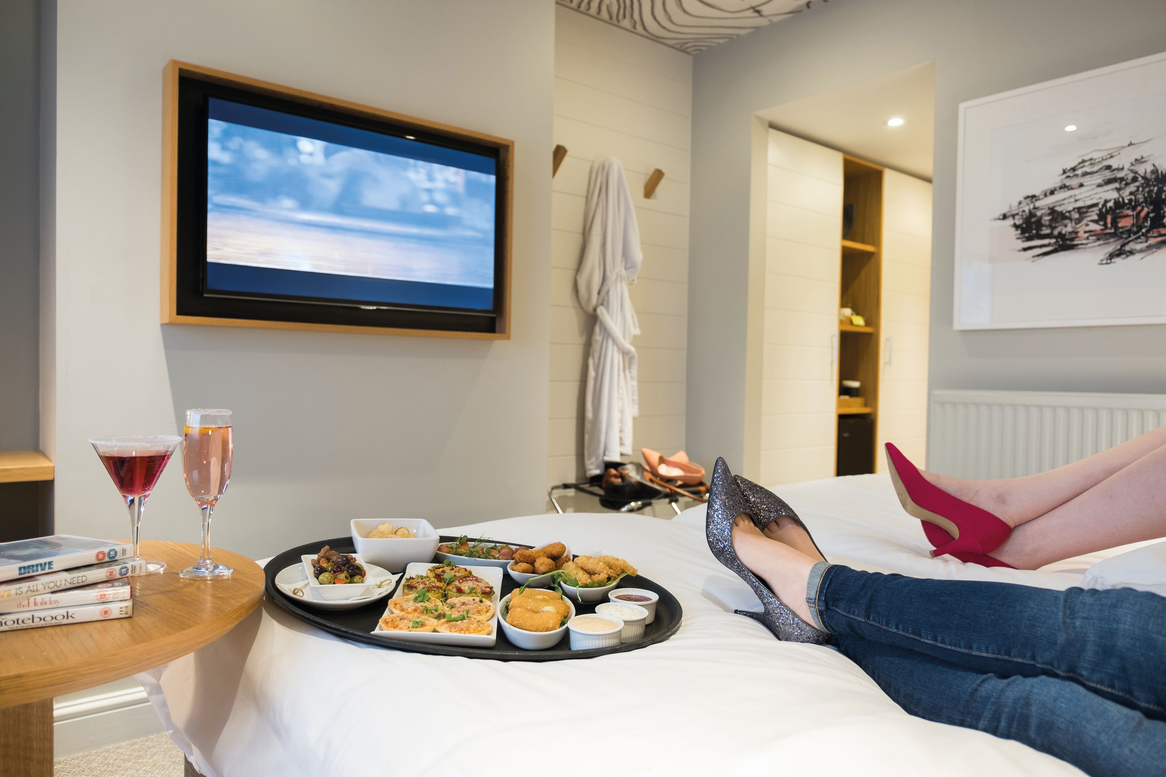 A selection of starters on a tray on the bed, with a number of DVDs to choose from beside wine glasses.