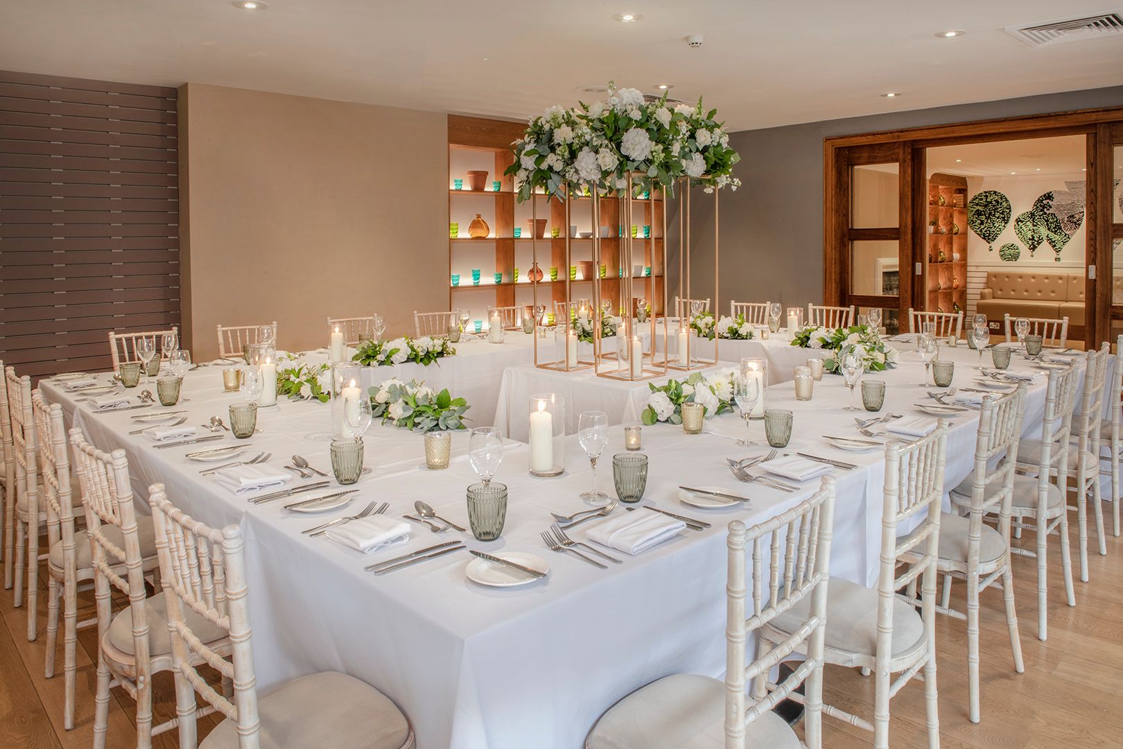 A large squared dinner table at a wedding, decorated with candles and flowers