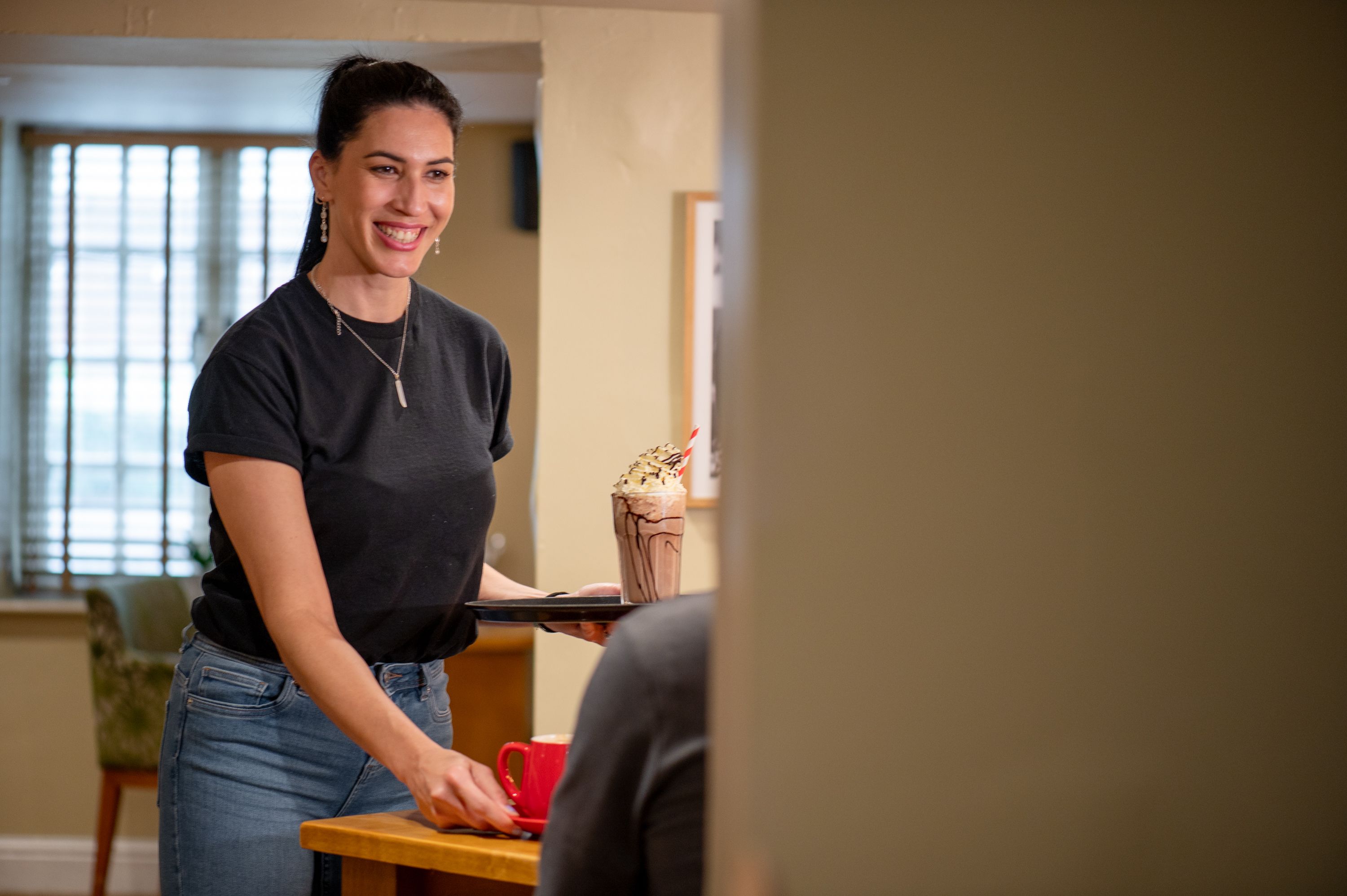 A lady smiling while serving a milkshake and drinks